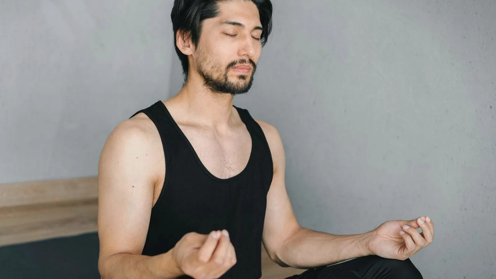 A man sitting cross-legged with his eyes closed and hands resting on his knees